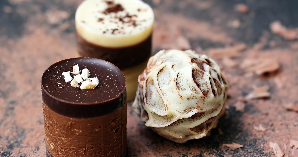Doces de chocolate com cobertura e confeitos sobre uma superfície marrom, ilustrando quantas calorias tem um brigadeiro